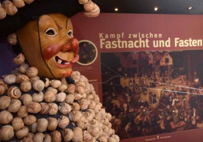 Narrenfigur vor Ausstellungstafel