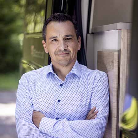 Mann lehnt sich an Wohnmobil an