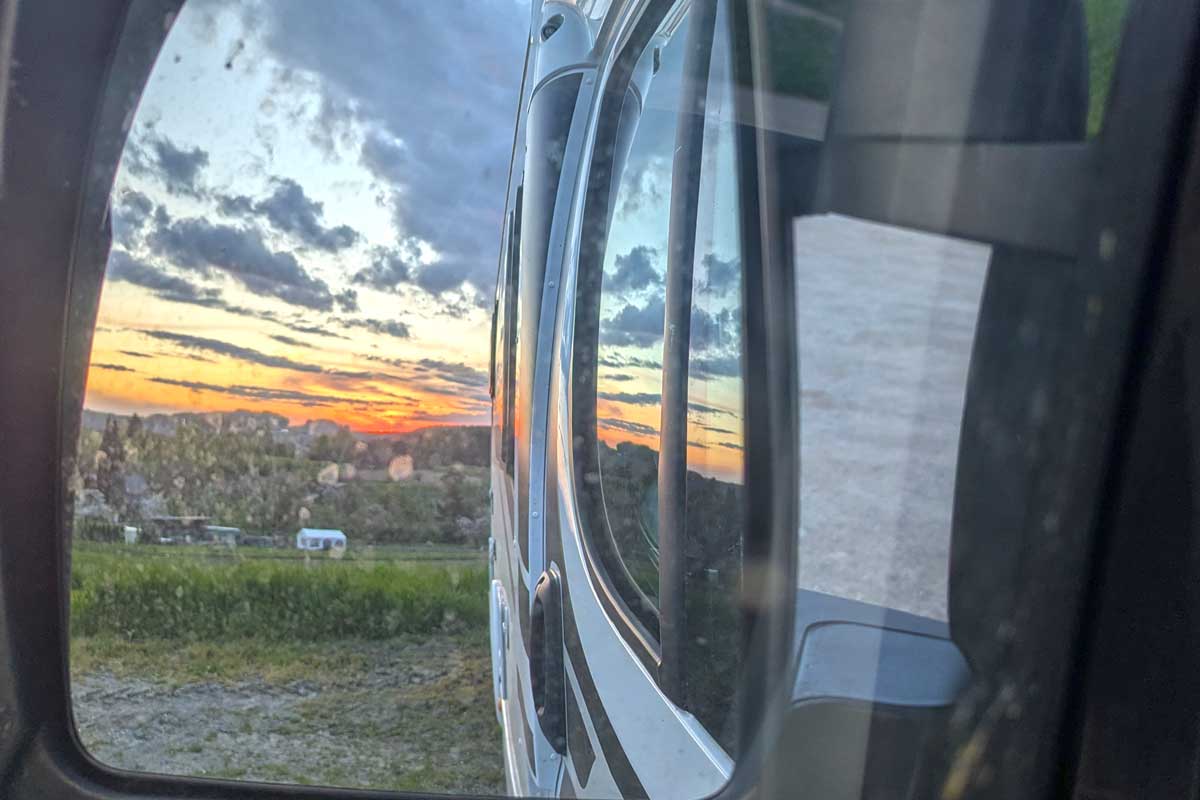 Blick in Rückspiegel bei Sonnenuntergang