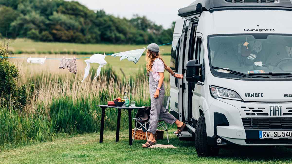 Frau steigt aus Campervan am See aus